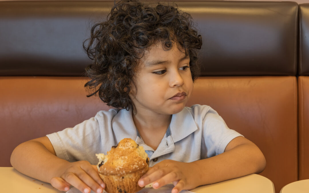 child eating a large sugar muffin