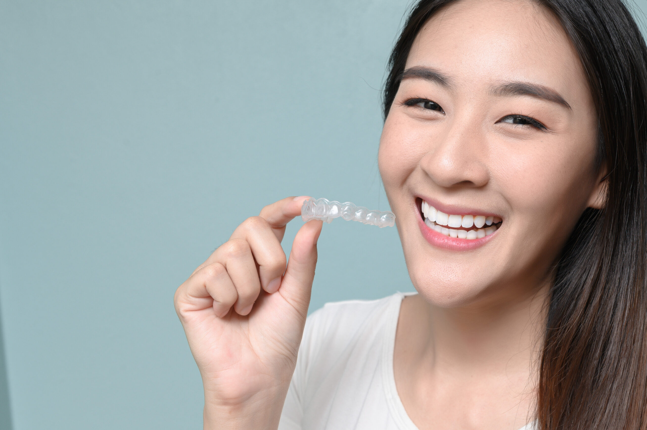 asian woman holding clear dental aligner