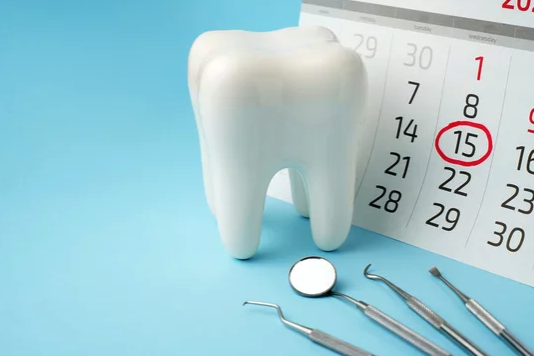 tooth next to a calendar with a date circled to remind people to schedule their dental appointments.